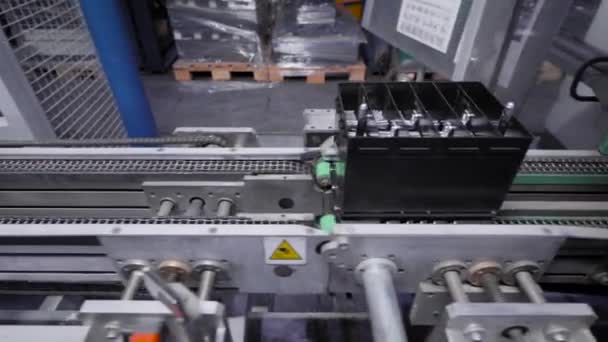 Linea automatica per il montaggio di batterie per auto. Le batterie nere si muovono e si raccolgono sul nastro trasportatore. — Video Stock