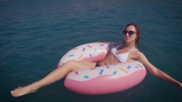 Glückliche junge Frau genießt das Meer und die Sonne. Schöne Frau schwimmt auf einem Gummiring. — Stockvideo