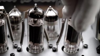 Bir elektronik mühendisi güç yükselticisine yeni bir radyo tüpü takıyor. Antika amfiler popüler..