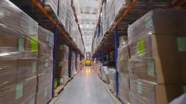 Malzeme parçaları raflarda depolanır. Sarı forklift sıraların arasından geçiyor..