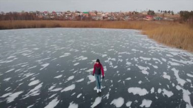 Hava görüntüsü. Güzel donmuş nehir ya da göl. Bir adam buzda kayıyor..