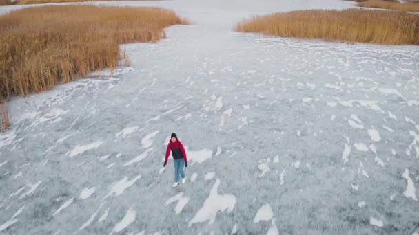 Vista aérea. Uma jovem está patinando em um lago congelado. — Vídeo de Stock