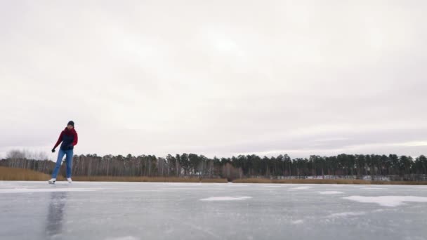 Jovem mulher está patinando no gelo na natureza. Os patins brancos são ótimos para diversão no inverno — Vídeo de Stock