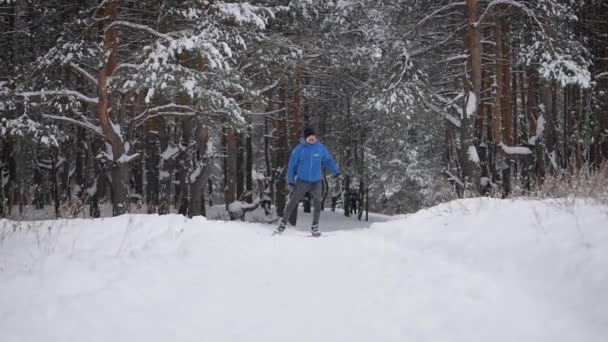 En ung man är engagerad i längdskidåkning i vinterskogen. Idrottaren springer skridskor. — Stockvideo