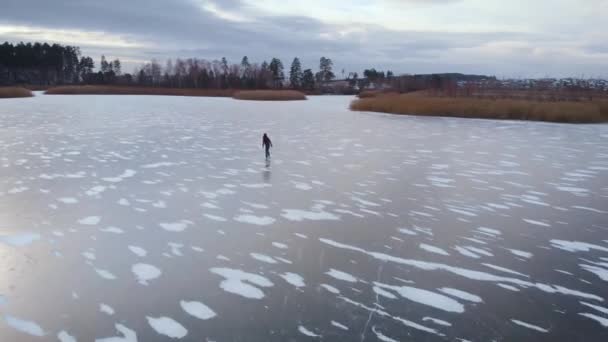 공중에서 본 모습. 아름다운 얼어붙은 강이나 호수. 한 남자가 얼음 위에서 스케이트를 타고. — 비디오