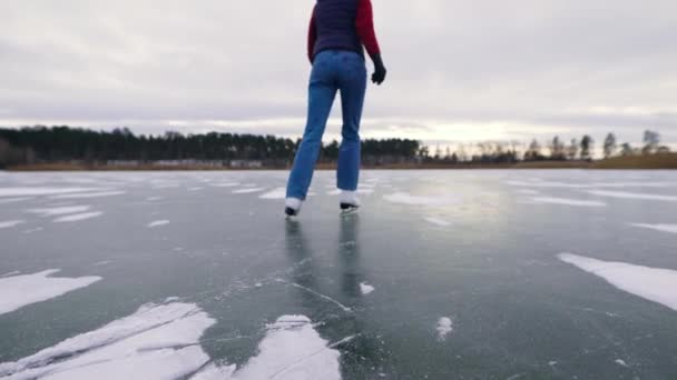 Genç ve güzel bir kadın buzda kayıyor. Göl dondu ve doğal bir buz pateni pistine dönüştü.. — Stok video