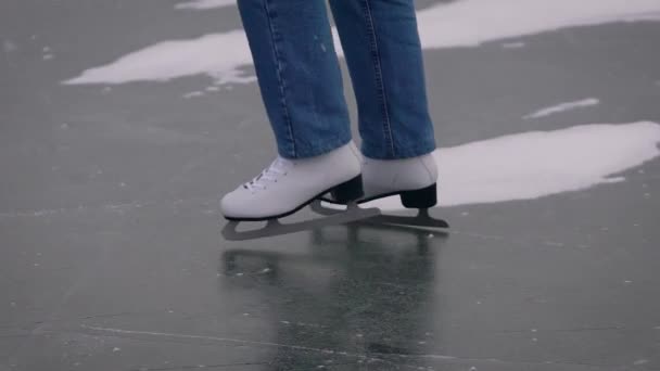 Patinaje sobre hielo en un lago congelado. En el marco, primer plano de las piernas en jeans y patines blancos. — Vídeos de Stock