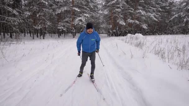 Een jongeman is bezig met langlaufen in het winterwoud. De atleet loopt schaatsen. — Stockvideo
