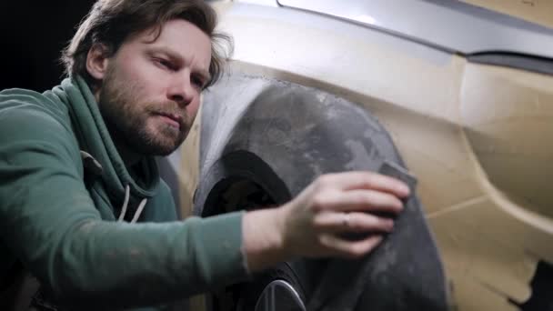 Hombre de diseño está puliendo la palanquilla de plastilina de detalle del automóvil en el garaje, la proyección de afinación del coche — Vídeo de stock