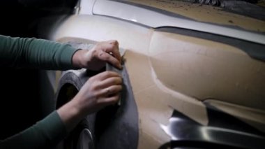 Erkek müteahhit, araba gövdesini oto servis atölyesinde kaplayan kilden detaylı prototip üretiyor.