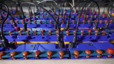 Fabrikada yeni pil şarj etmek için bir tezgah. Araba aküleri seri olarak birbirine bağlıdır.