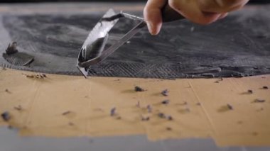 Tasarımcı atölyedeki metal bıçakla endüstriyel kil parçalarını kesiyor.