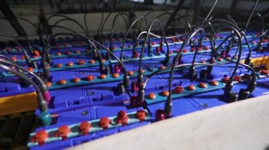 Fabrikada yeni pil şarj etmek için bir tezgah. Araba aküleri seri olarak birbirine bağlıdır.