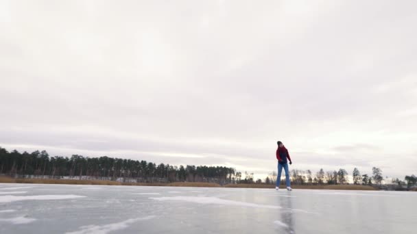 まともな若い女性は自然の中で氷の上でスケートしています.白いスケートは冬の楽しみのために素晴らしいです — ストック動画