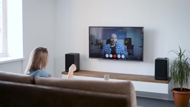 Eine Frau spricht zu Hause per Videoschaltung. Video-Chat im Fernsehen mit dem Freund. — Stockvideo