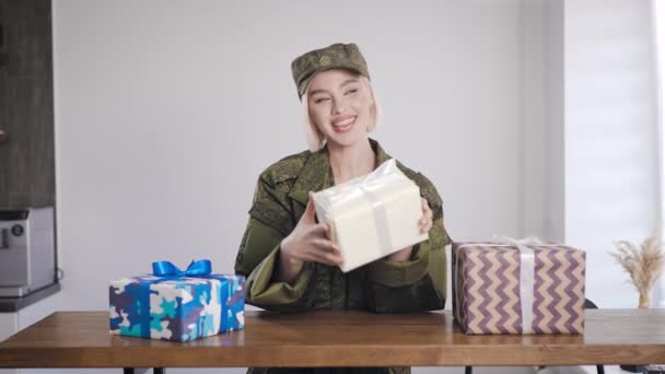 군복을 입은 금발의 여자가 선물을 손에 들고 있다. 놀라운 것은 박스 안에 있습니다.. — 비디오