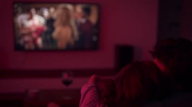 Tatlı genç bir çift akşam televizyon izliyor. Ekranda romantik bir komedi. Bir erkek ve bir kadın sarılıp dinleniyor.