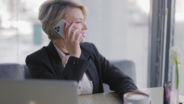 Zakenvrouw in een café aan de telefoon. — Stockvideo