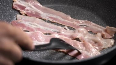 Aşçı tavada sulu pastırma kızartıyor. Çok leziz ve besleyici bir et parçası..