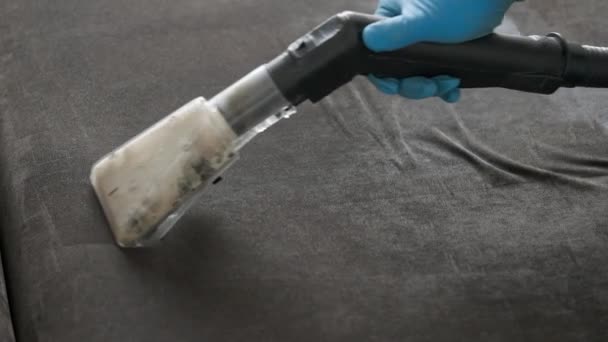 Profesionální úklid. Mužský dělník používá prací vysavač k čištění pohovky.. — Stock video
