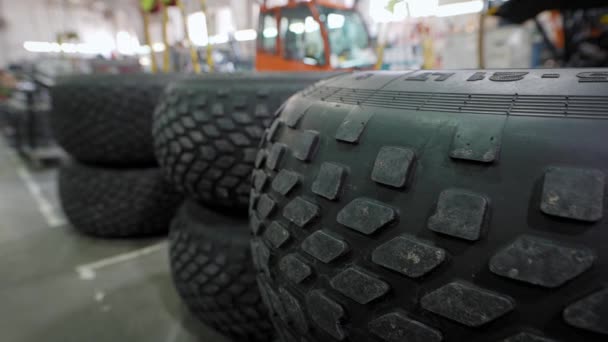 En primer plano hay enormes ruedas de vehículos todo terreno o camiones. taller de montaje automotriz de la empresa. — Vídeo de stock