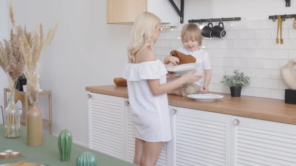 Mamá e hijo en una cocina luminosa. Juntos, las tareas domésticas son más divertidas. — Vídeos de Stock