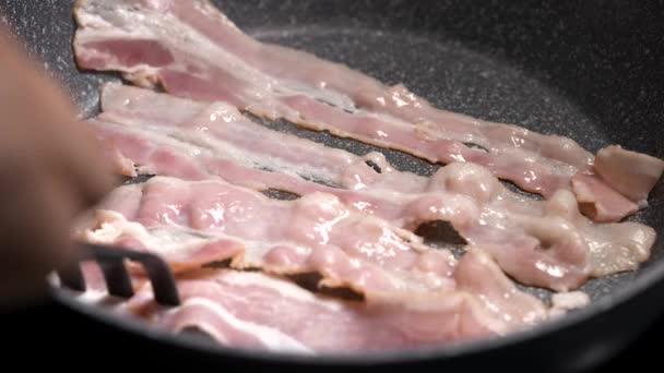 Makró felvétel a szalonna főzési folyamatról. Az étvágygerjesztő húsdarabokat serpenyőben sütik.. — Stock videók