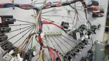 Otomotiv elektriğini değiştirmek için özel bir duruş. Bir işçi bir röleyle bir elektrik devresi kurar.