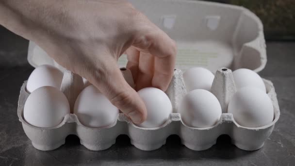 Ovo de galinha ao pequeno-almoço. Uma mão de homem tira um ovo da caixa. — Vídeo de Stock