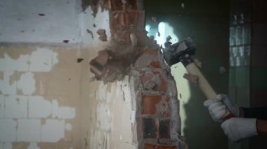 Elinde balyoz olan bir işçi tuğla duvarı yıkar. Hayattaki ve işteki engelleri aşma kavramı.