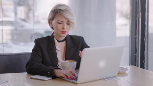 La donna lavora con un computer portatile in un caffè. Internet ti permette di fare affari da qualsiasi parte del mondo. — Video Stock