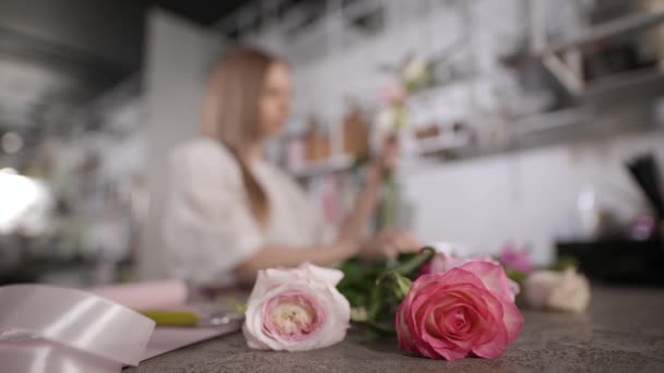 Una florista mujer en el lugar de trabajo recoge un arreglo floral. — Vídeos de Stock