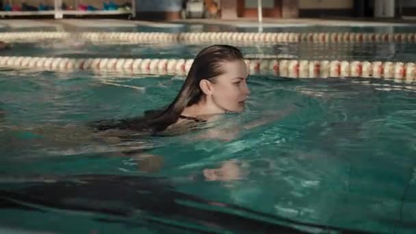 Женщина плавает в бассейне. Плавание полезно для здоровья — стоковое видео