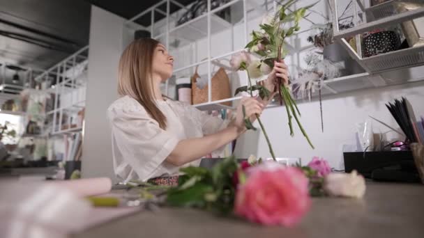 Жінка-флорист на робочому місці збирає квіткову композицію . — стокове відео