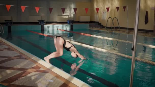 一个纤细的黑发姑娘跳进了游泳池.度假时玩乐的女人. — 图库视频影像