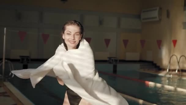 La donna in piscina si pulisce con un asciugamano. Bruna attraente e allegra dopo il nuoto — Video Stock