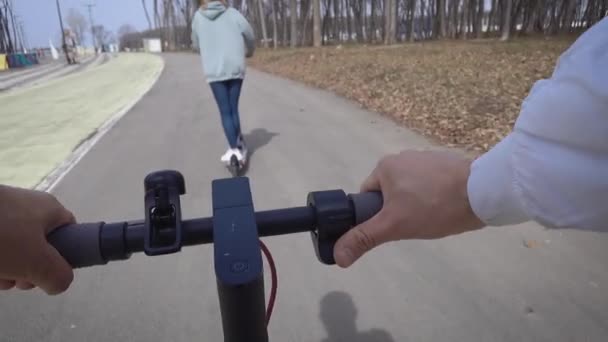 Vista en primera persona. Un hombre sigue a una mujer en su scooter eléctrico. — Vídeos de Stock