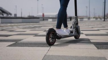 Elektrikli scooter 'da kadın bacakları. Bir kadın şehirde scooter kullanıyor..
