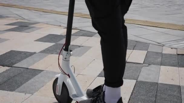 Ein junger Mann in weißer Jacke und Sonnenbrille fährt mit einem Elektroroller. Unterhaltung — Stockvideo