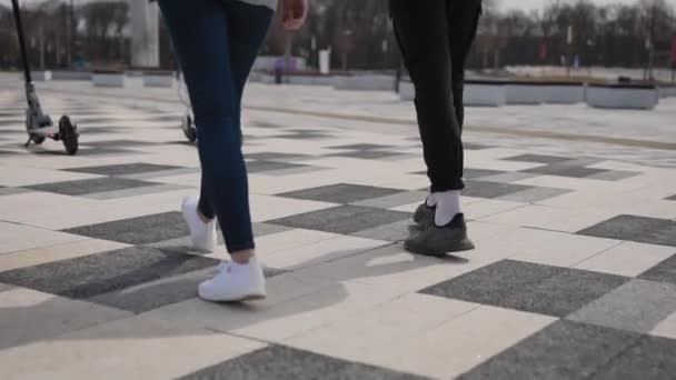 A man and a woman ride electric scooters. In the frame, the legs and footboards of scooters. — Stock Video