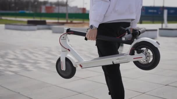 Un uomo irriconoscibile sta portando uno scooter elettrico. Lo scooter è costruito compattamente. — Video Stock