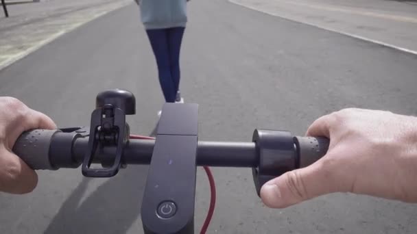 Pandangan orang pertama. Seorang pria mengikuti seorang wanita menggunakan skuter listrik. — Stok Video
