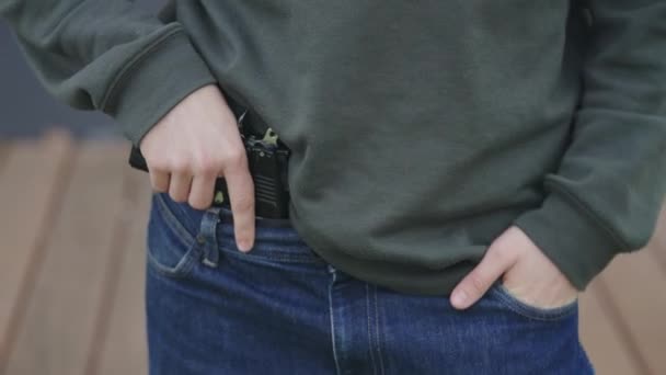 The man is hiding the gun in his pants. Illegal carrying of firearms — Stock Video