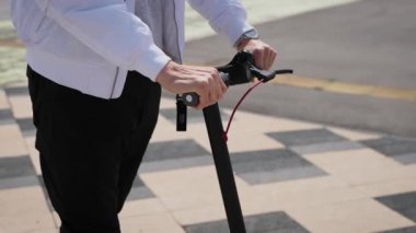 Ellerini direksiyona yakın çekim yap. Adam elektrikli scooterı kontrol ediyor..