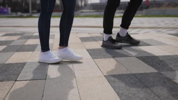 A man and a woman walk along the sidewalk. Side view of the legs in sneakers — Stock Video