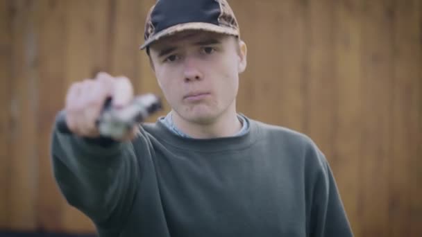 Een tiener met een pistool in zijn handen dreigt. De man is agressief en klaar om te handelen.. — Stockvideo