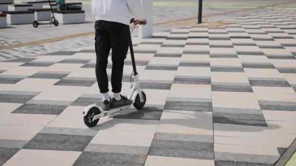 Mens pieds en baskets sur un scooter électrique. Transport urbain électrique des jeunes. — Video