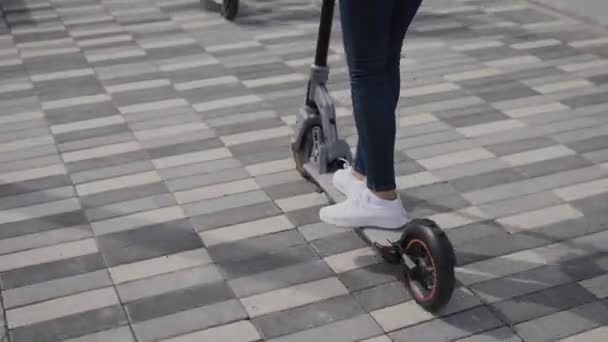 Gambe delle donne su uno scooter elettrico. Una donna sta guidando uno scooter in giro per la città. — Video Stock