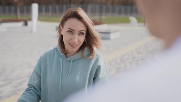 Een man en een vrouw gekleed in casual stijl, praten op straat. — Stockvideo