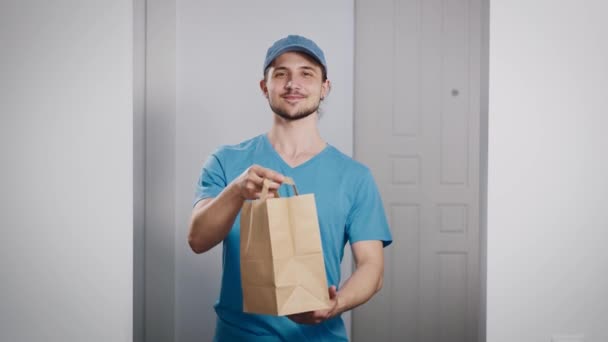 Un livreur a ramené une commande d'un restaurant. Beau jeune homme dans un T-shirt et une casquette. — Video